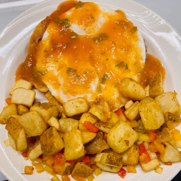 Huevos Rancheros with a fried egg, salsa, and a side of crispy home fries with peppers.